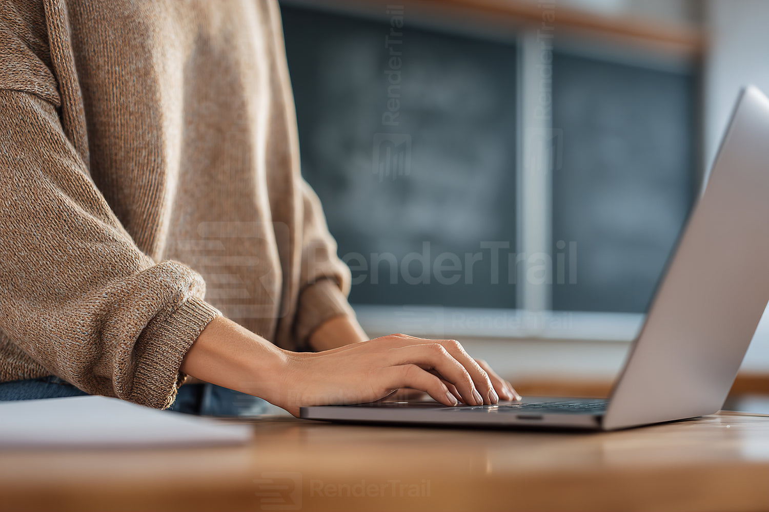 Young adult working on a laptop in a cozy classroom setting with wooden desk and chalkboard in the background