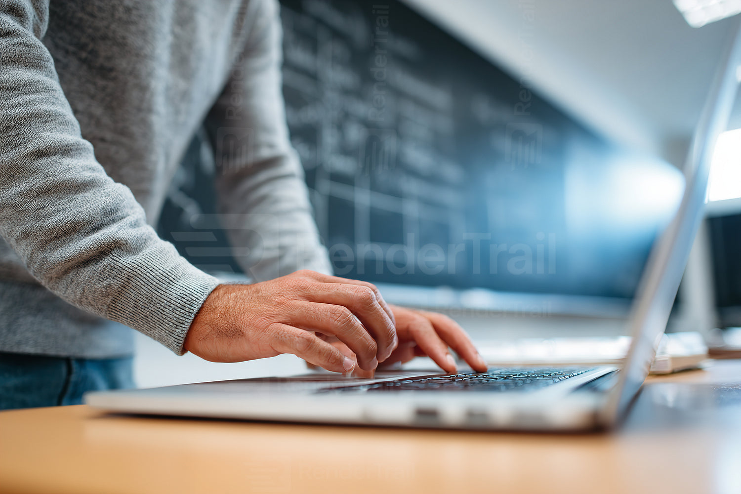 Individual working on a laptop in a bright classroom with instructional materials displayed on the blackboard